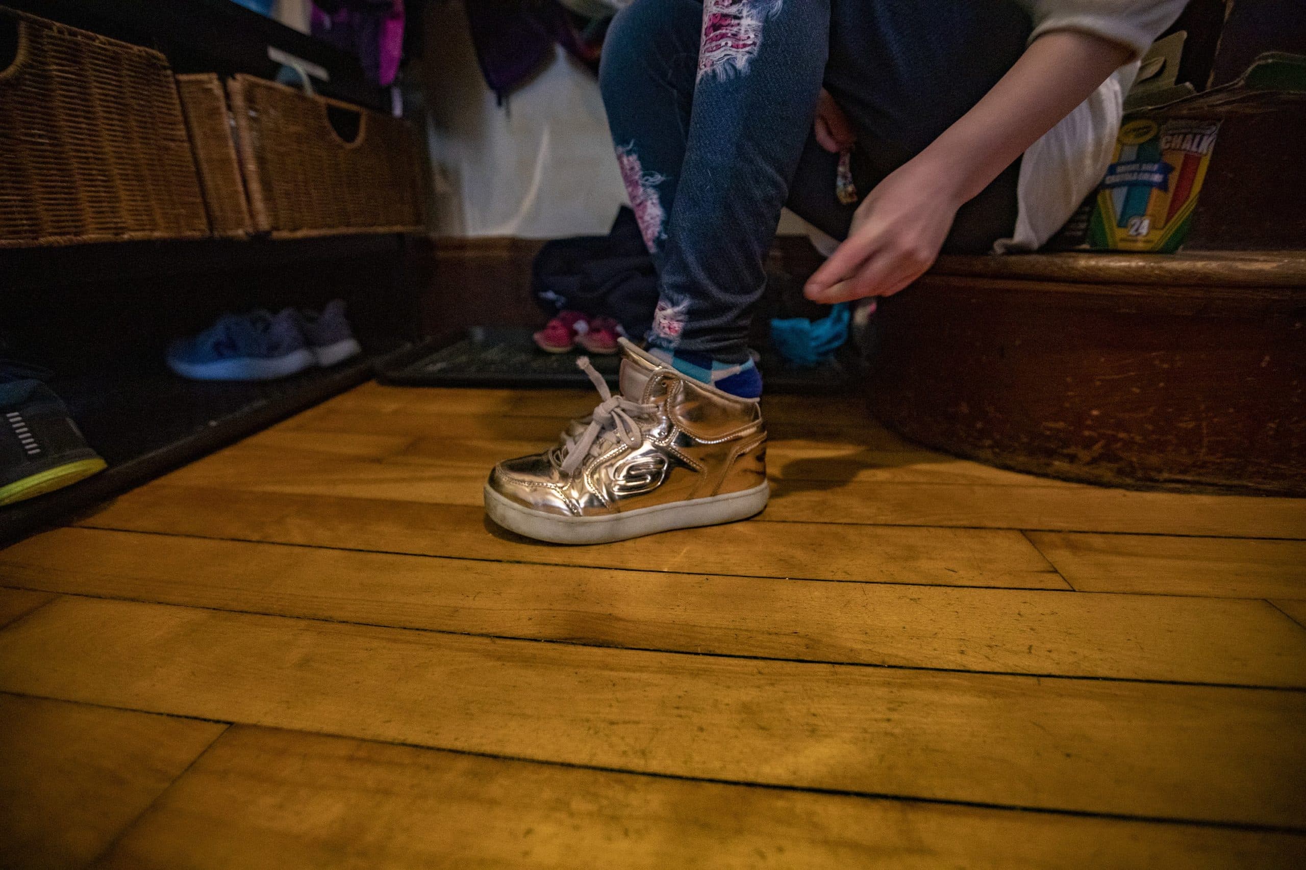 Hallel puts on their gold sneakers to go to the playground with the family. (Jesse Costa/WBUR)