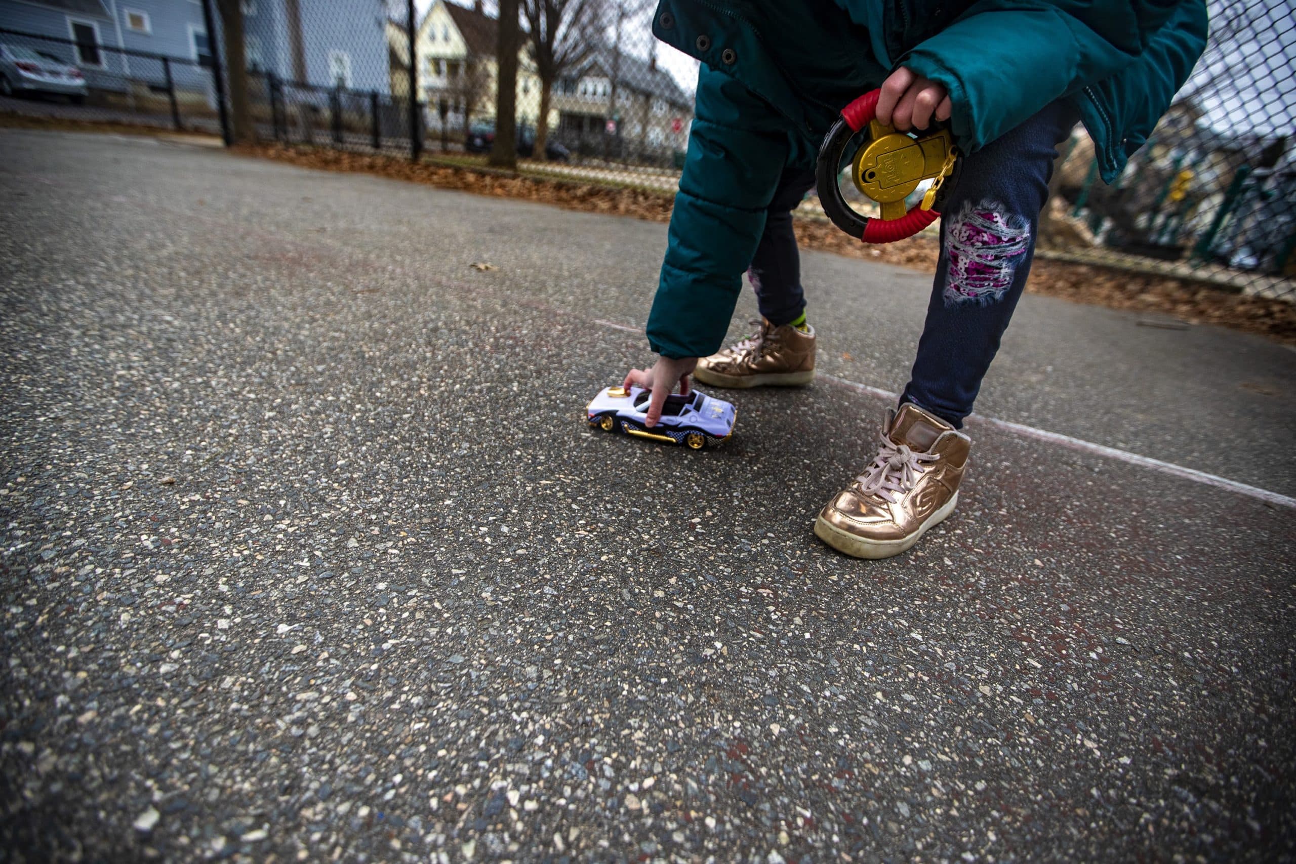 Hallel places their remote control car on to the ground while playing in the playground. (Jesse Costa/WBUR)