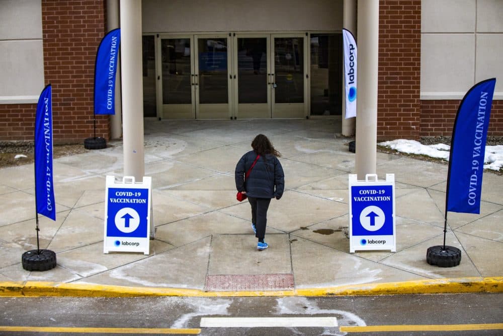 A woman walks into a vaccination site at the Natick Mall earlier this year. (Jesse Costa/WBUR)