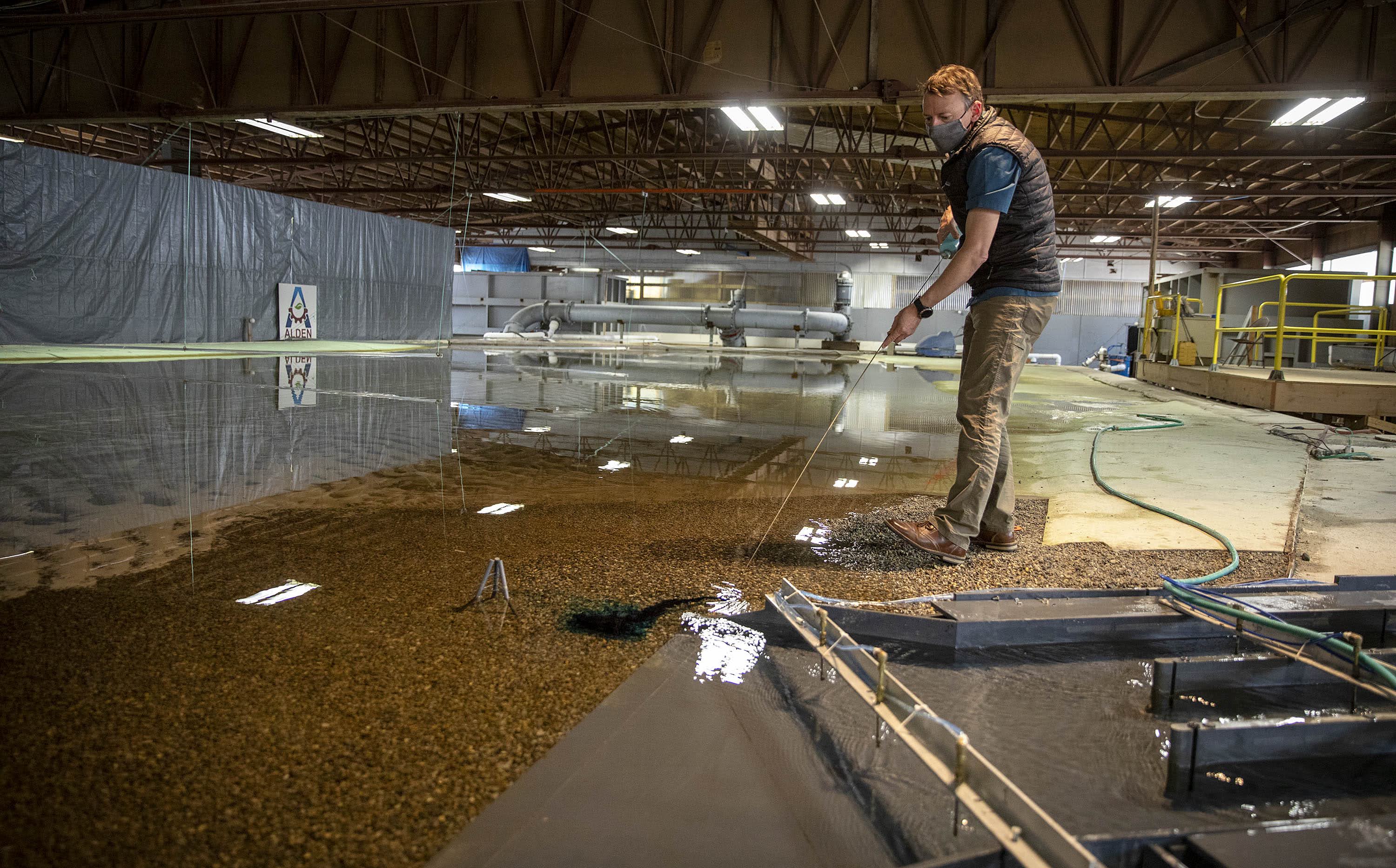 Dan Gessler creates an ink trail in the water of the model Mississippi river at the entrance to the sediment diversion structure. (Robin Lubbock/WBUR)