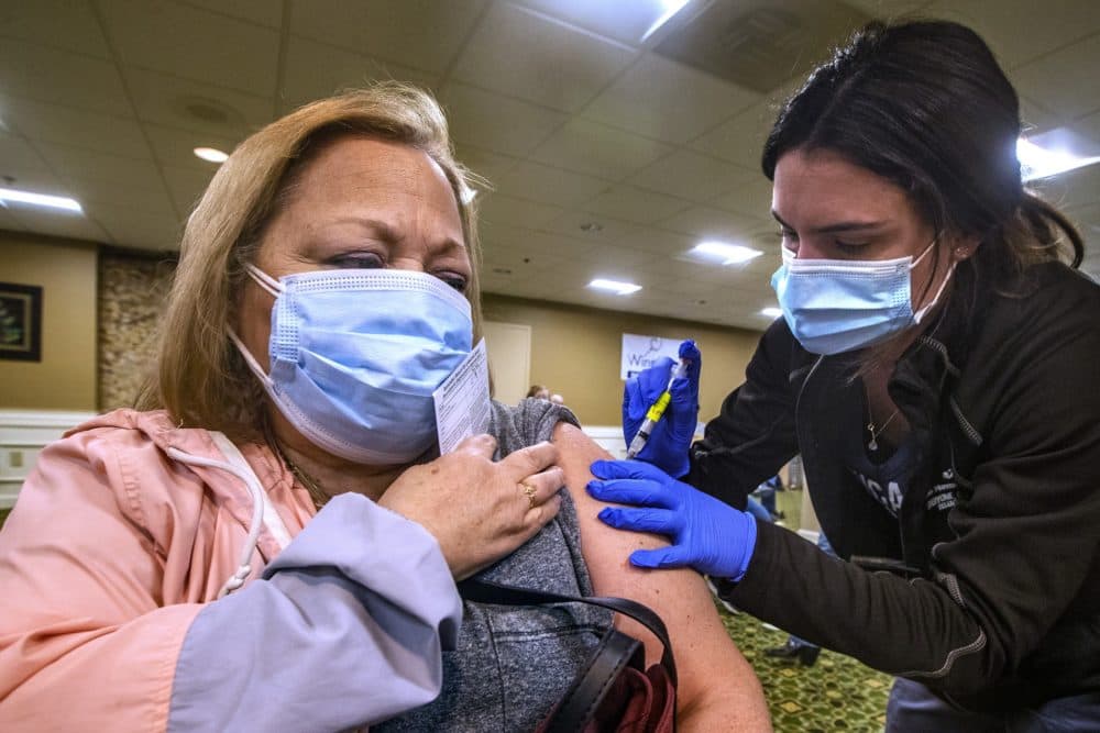 Margaret Connolly holds her sleeve while registered nurse Jessica Kazanovicz administers her second Moderna dose. (Jesse Costa/WBUR)