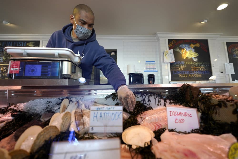 Worker Cori Malone, of Provincetown, Mass., arranges seaweed near fish at Mac's Seafood Market, April 6, 2021, in Provincetown.(Steven Senne/AP)