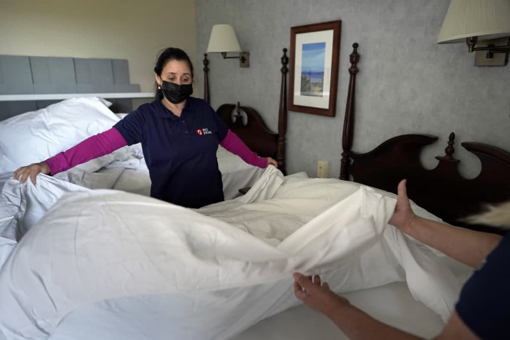 Workers Miriam Mattos, left, and Marilene Souto, hands only at right, both of Hyannis, Mass., make a bed, April 6, 2021, at Red Jacket Resorts, in Yarmouth, Mass. (Steven Senne/AP)
