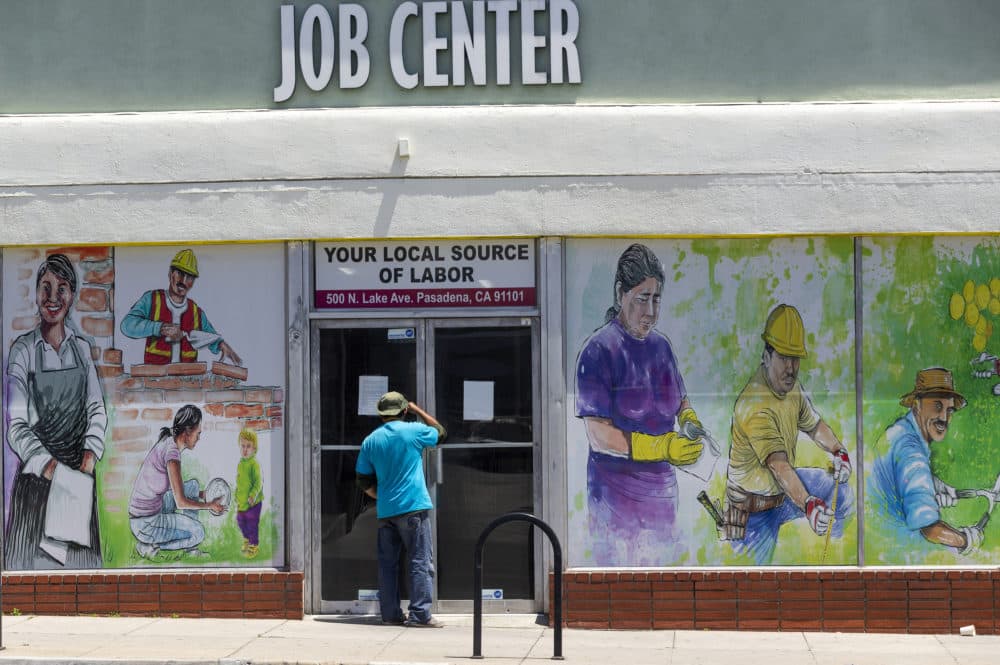 In this May 7, 2020, file photo, a person looks inside the closed doors of the Pasadena Community Job Center in Pasadena, Calif., during the coronavirus outbreak. (Damian Dovarganes/AP File)