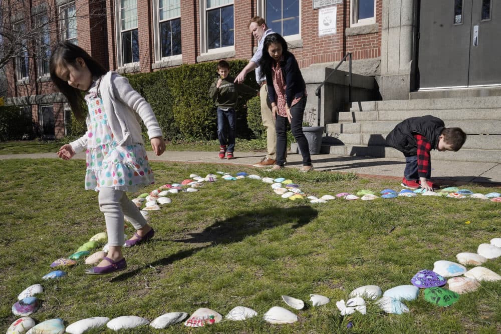 Sofia Horrigan, 4, of Quincy, Mass., left, examines a heart made of seashells with family members, from behind left, Conor, 8, John Horrigan, his wife Kim, and their son William, 3, right, while gathered for a photograph, April 13, 2021, at the school, in Quincy. (Steven Senne/AP)