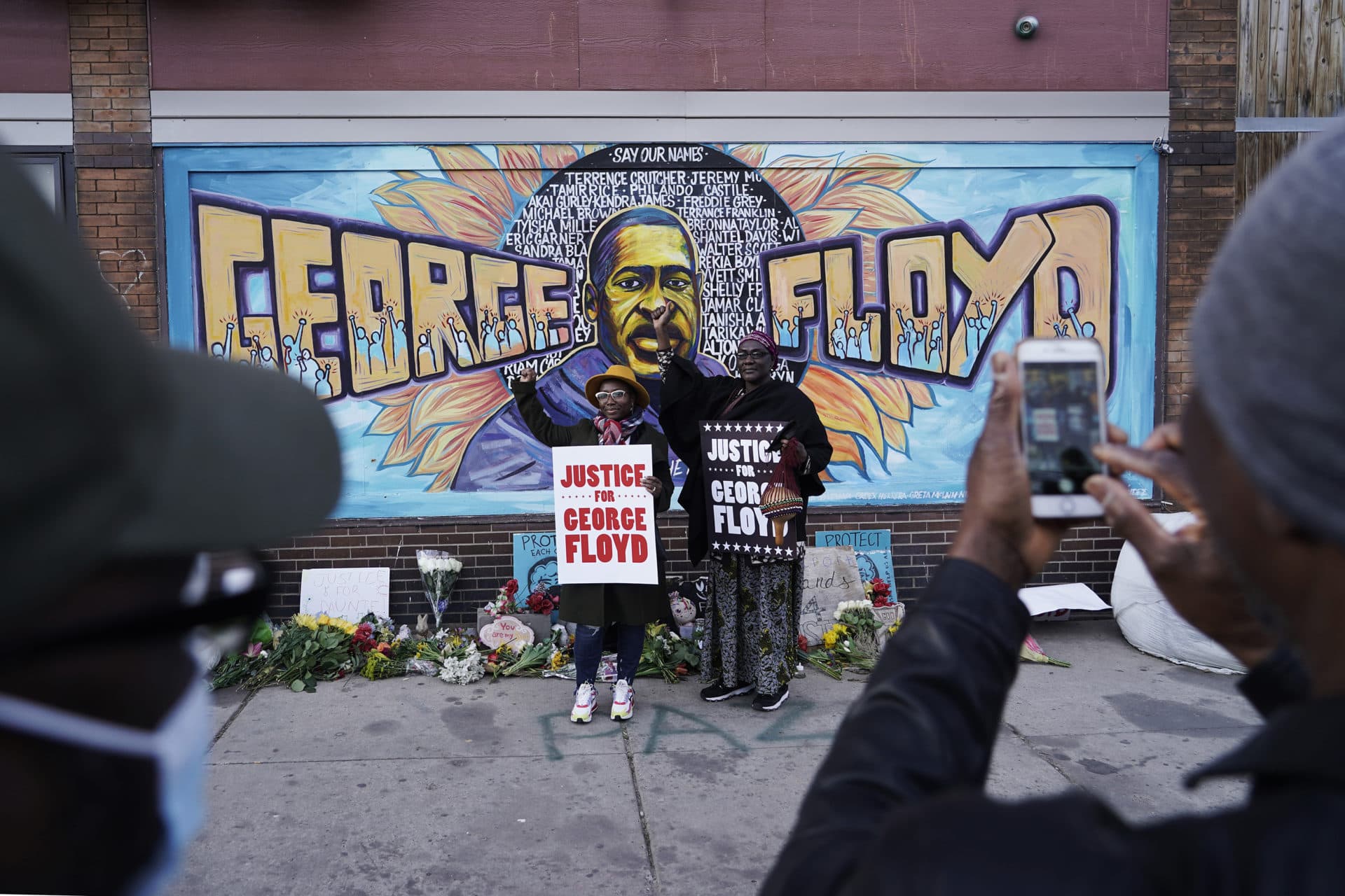 People pose for pictures in front of a mural for George Floyd. (Morry Gash/AP)