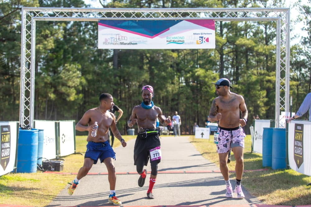 Prolyfyck founder William Jones III (center) finishes his first marathon with co-founder James Dowell cheering by his side. (Derrick J. Waller)
