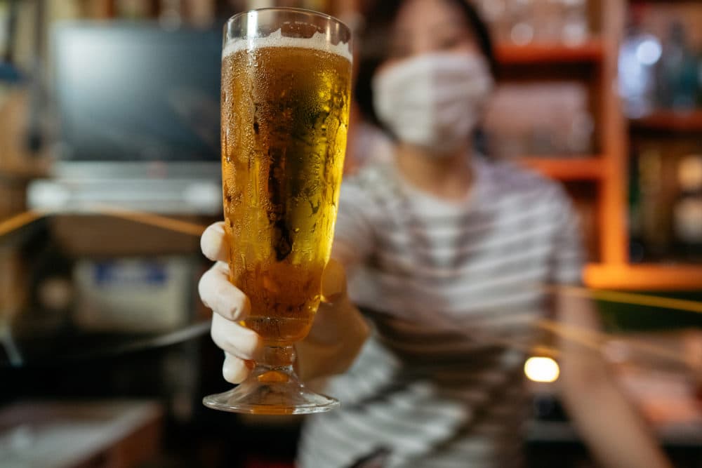 A masked bar owner serves beer during the pandemic. (Getty Images)