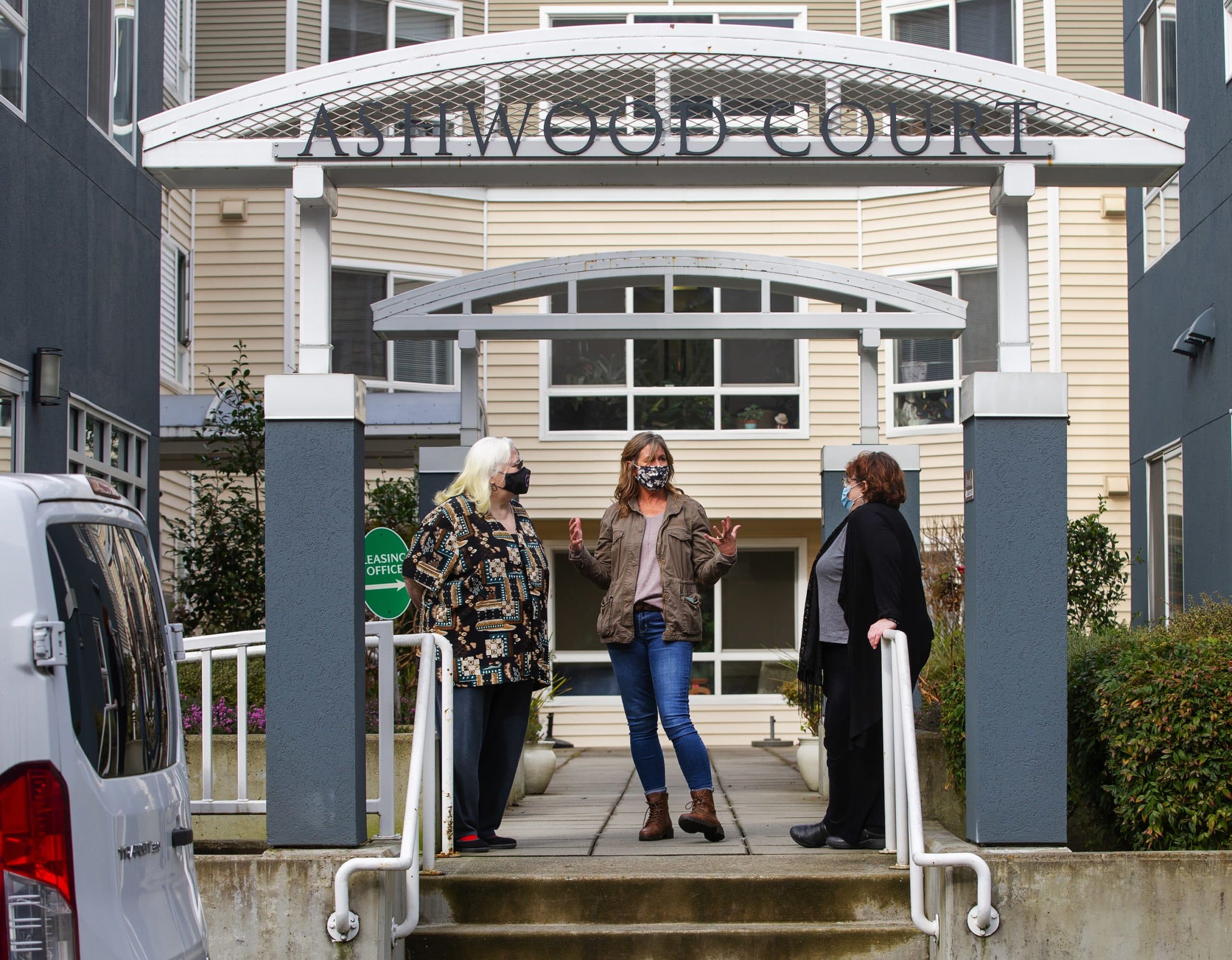 The Ashwood Court low-income housing apartments in Bellevue, Washington. Kim Loveall Price, center, director of the nonprofit that operates the units, talks with residents Susan Sherman, right, and Joyce Hansbearry. (Mike Seigel for WBUR)