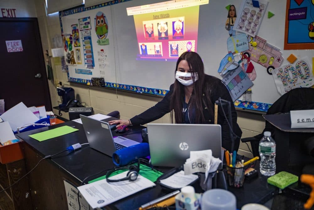 In addition to the students she has in class, Carmen Rios attends to her kindergarten students who are attending class remotely using her laptop at Barbieri Elementary School in Framingham. (Jesse Costa/WBUR)