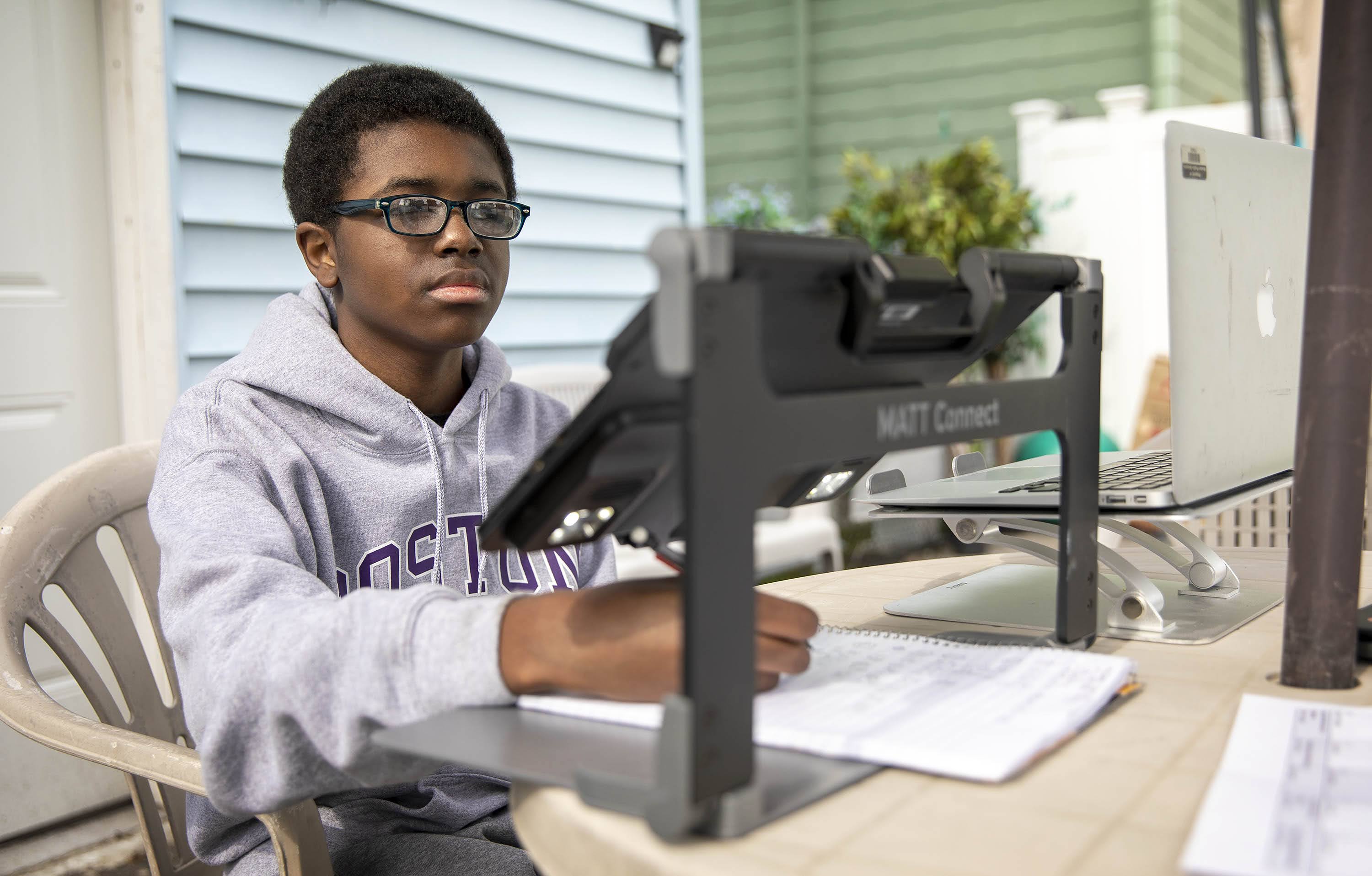 Michael Besson works on his homework in his backyard. (Robin Lubbock/WBUR)