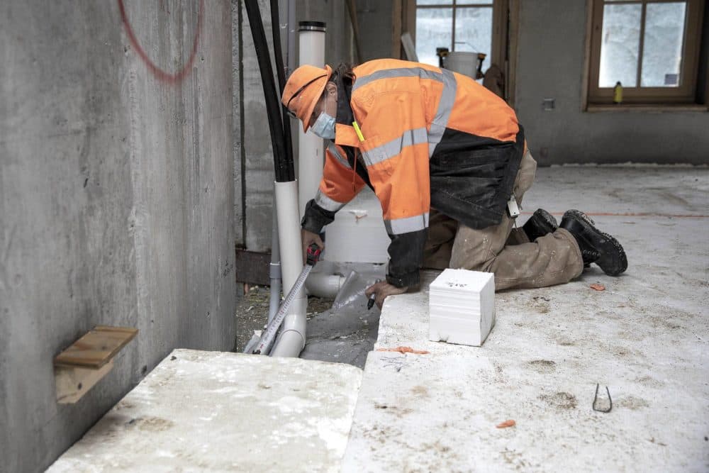 Stephen Moore works on filling the space which will be under the ground floor with a thick layer of insulation. (Robin Lubbock/WBUR)