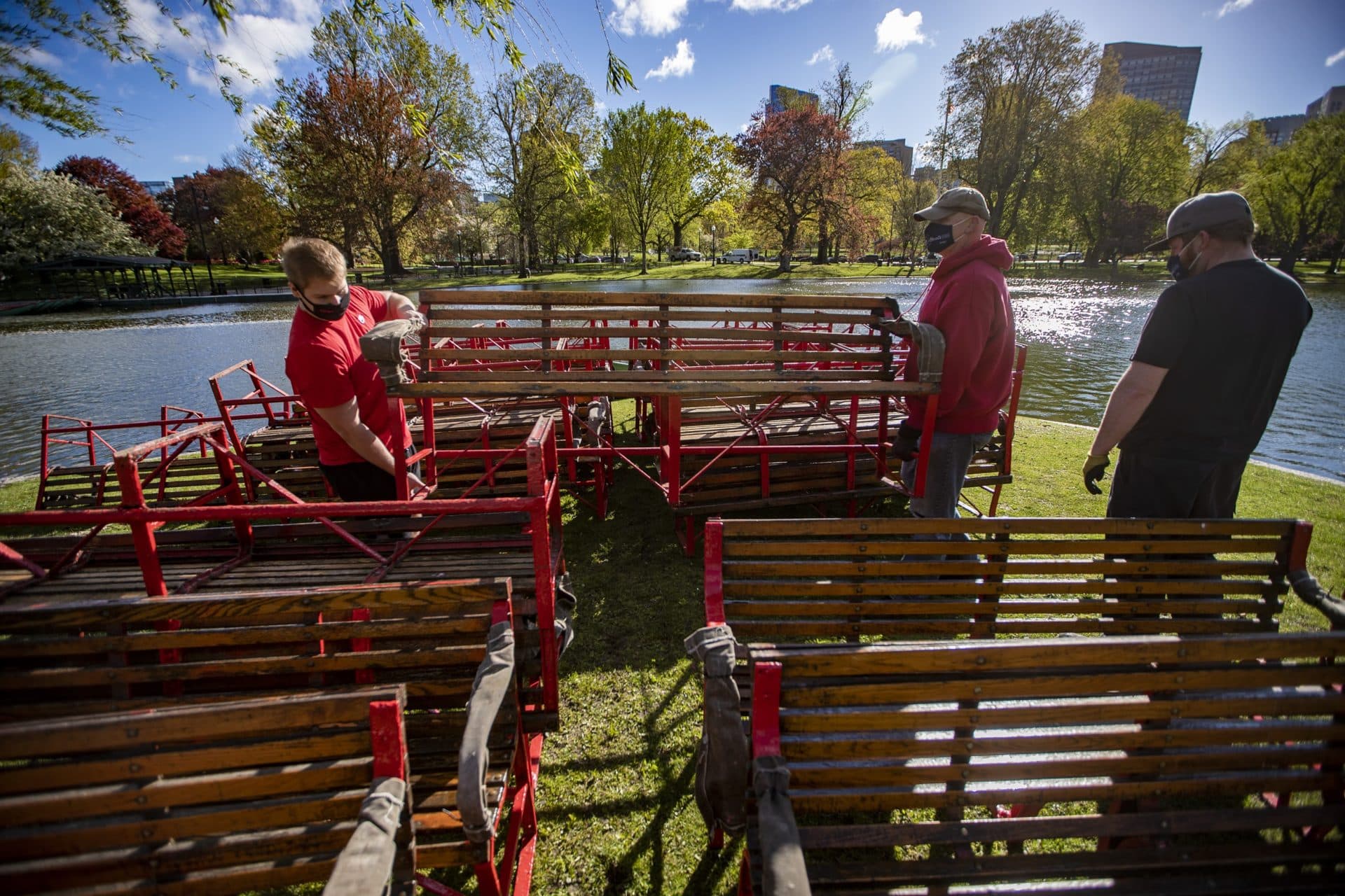 Workers lift a bench off one of the swan boats to be mounted onto a pontoon. (Jesse Costa/WBUR)