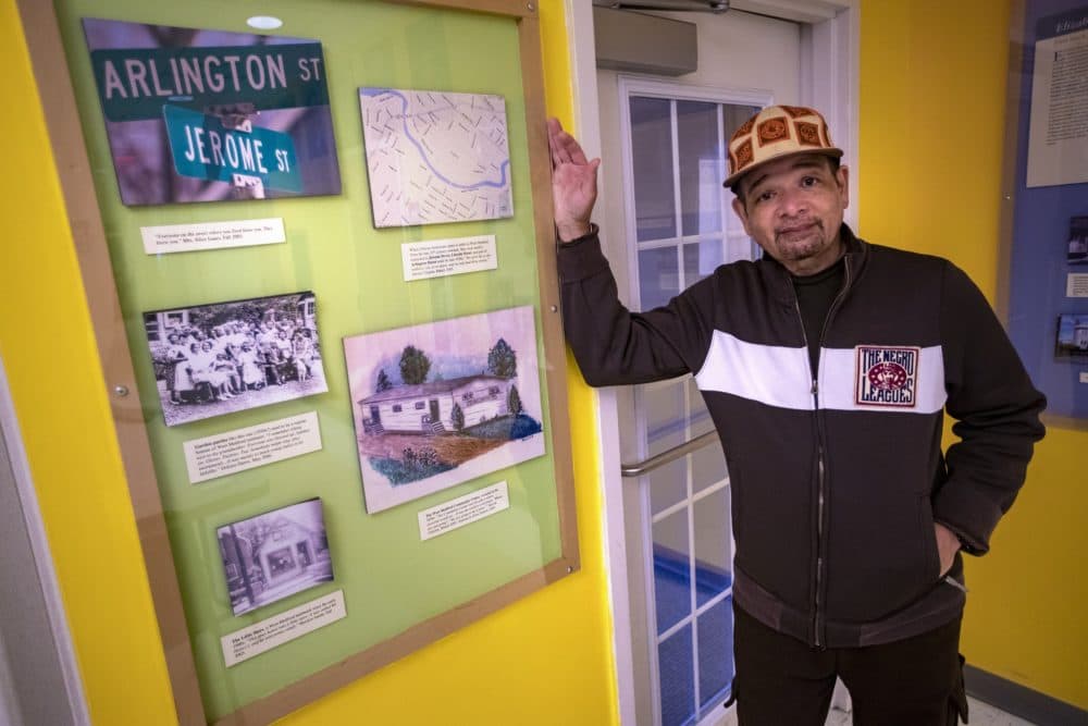 Poet Terry Carter stands beside old photographs and illustration that tell the history of the West Medford Community Center. (Jesse Costa/WBUR)