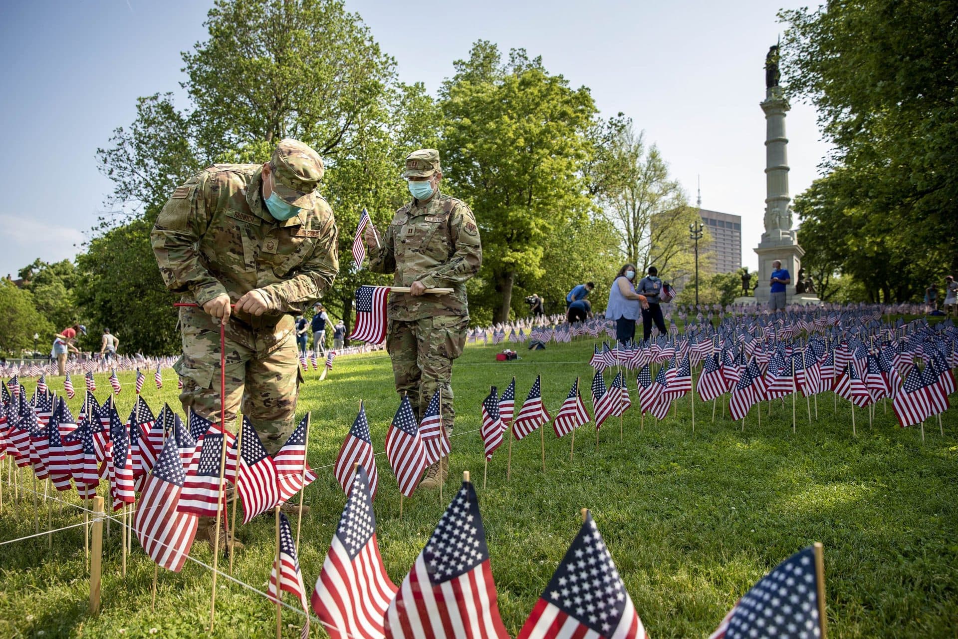MSgt. Mark Radwich and Capt. Ann Marie Leifer of the 102nd Medical Group, Mass. Air National Guard, plant flags on Boston Common Wednesday ahead of Memorial Day. (Robin Lubbock/WBUR)