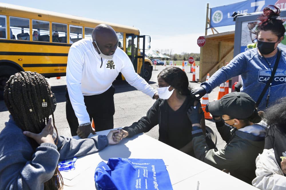 East Hartford High School senior Sudeen Pryce, right, center, receives support from classmate Alexia Phipps, left, East Hartford High School Intervention Coordinator Mark Brown, second from left, and EMT Katrinna Greene, top right, of Manchester, as RN Kaylee Cruz of Bristol administers a shot to Pryce at a mass vaccination site at Pratt &amp; Whitney Runway in East Hartford, Conn., Monday, April 26, 2021. (AP Photo/Jessica Hill)