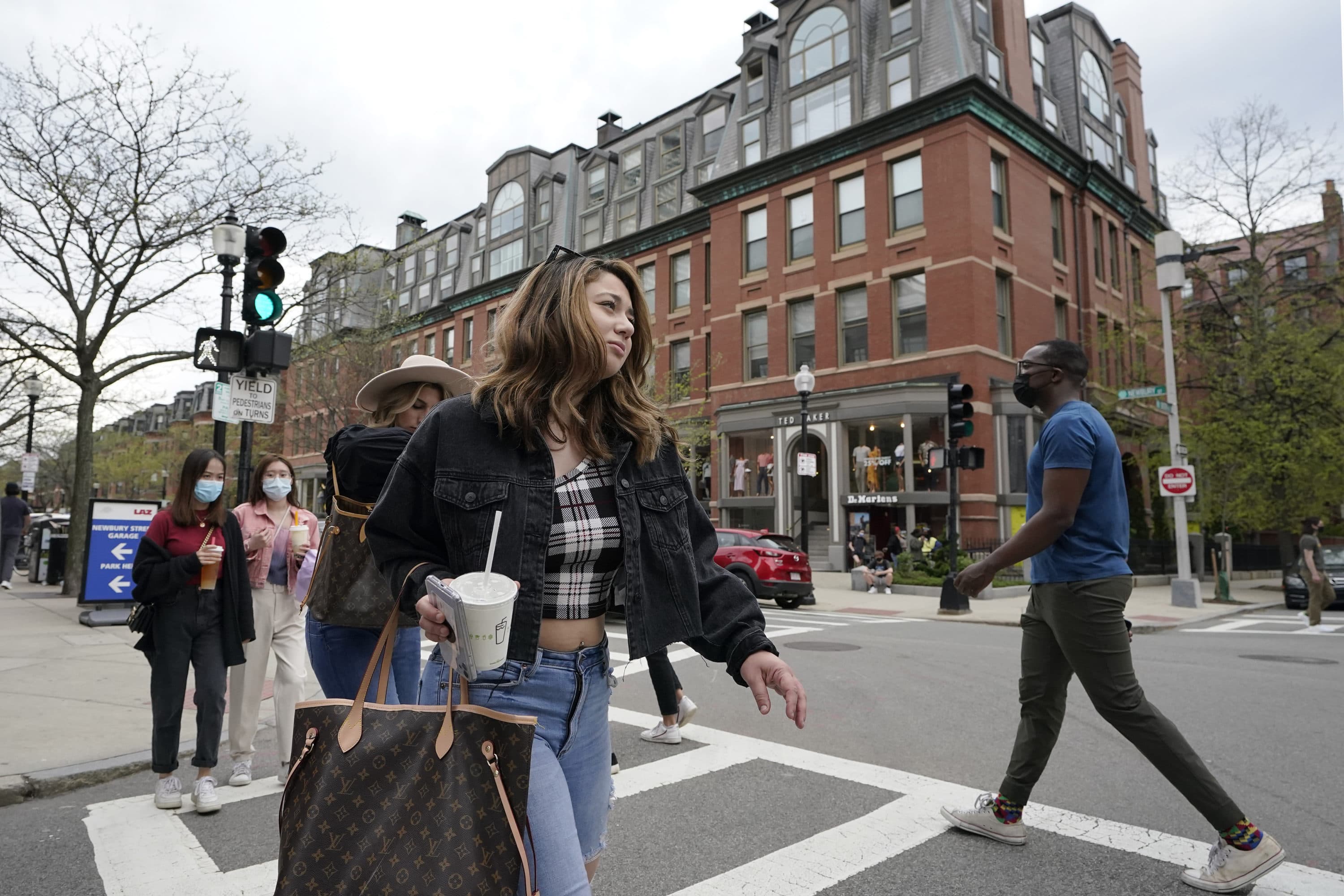 Pedestrians, some wearing masks out of concern for the coronavirus, while others go without masks, walk along Boston's fashionable Newbury Street, May 2, 2021.(Steven Senne/AP)