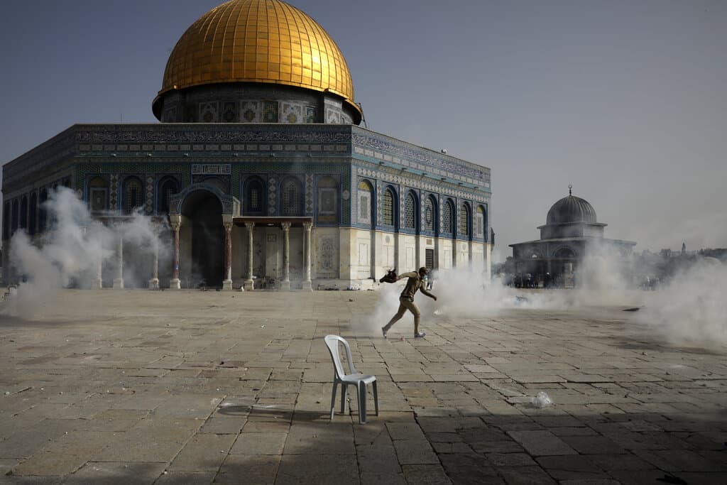 A Palestinian man runs away from tear gas during clashes with Israeli security forces in front of the Dome of the Rock Mosque at the Al Aqsa Mosque compound in Jerusalem's Old City Monday, May 10, 2021. (Mahmoud Illean/AP)