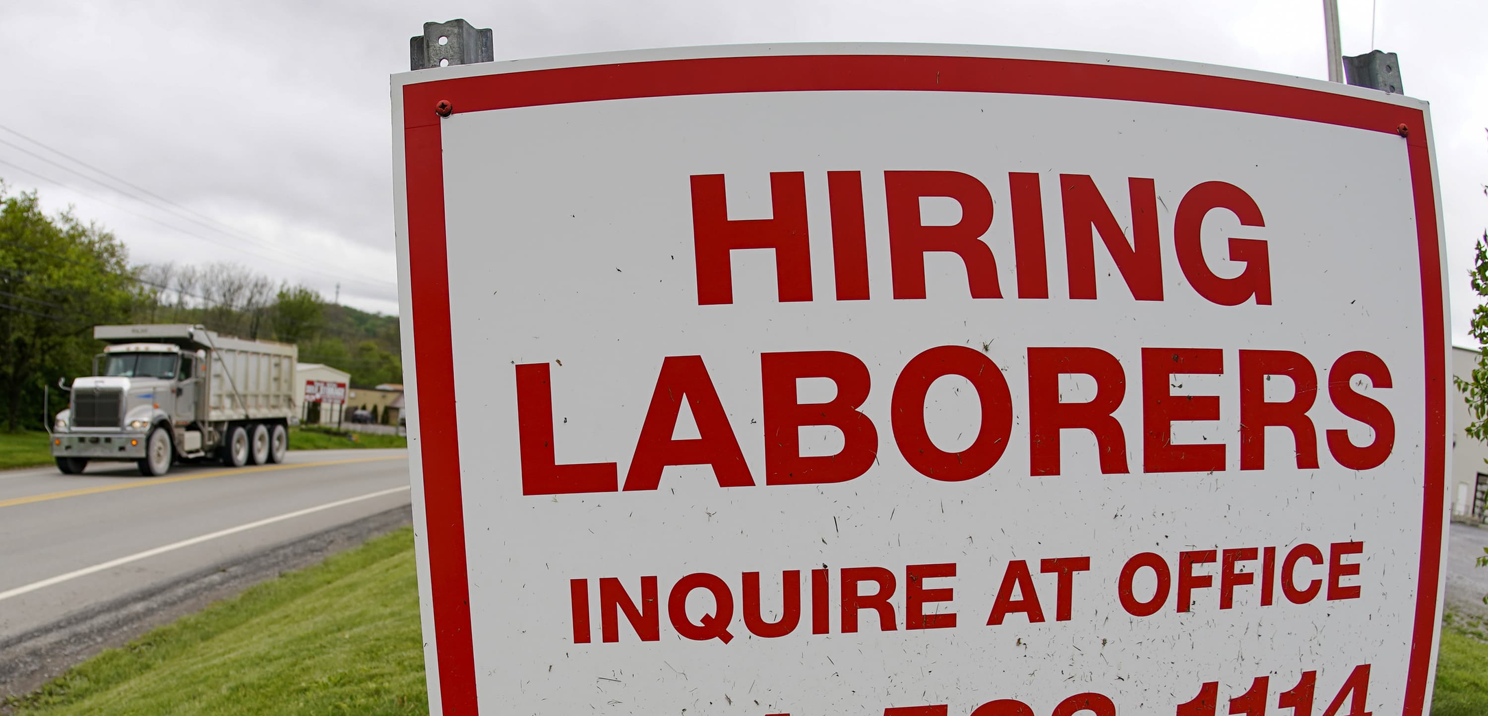 On May 5, 2021, a truck passes a sign showing a need to hire laborers outside a concrete products company in Evans City, Pa. (Keith Srakocic/AP File)