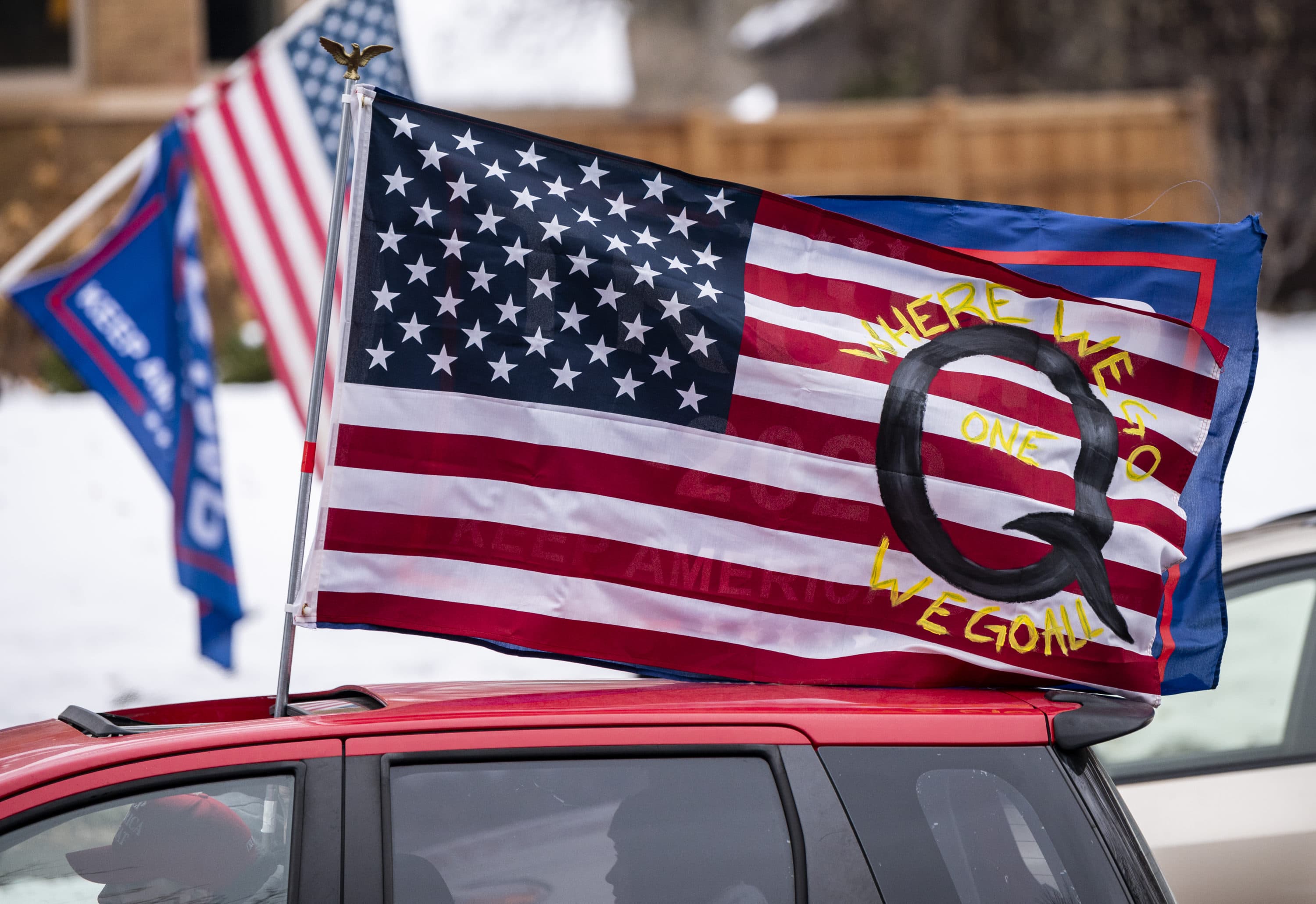 ST PAUL, MN - NOVEMBER 14: A car with a flag endorsing the QAnon drives by as supporters of President Donald Trump gather for a rally outside the Governor's Mansion on November 14, 2020 in St Paul, Minnesota. Thousands have gathered in cities around the country today to contest the results of the election earlier this month. (Photo by Stephen Maturen/Getty Images)