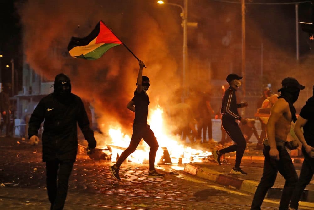Palestinian protesters hurl stones during clashes with Israeli forces in the Shuafat Palestinian neighbourhood, neighbouring the Israeli settlement of Ramat Shlomo, in Israeli-annexed east Jerusalem on May 14, 2021. (Ahmad Gharabli/AFP via Getty Images)
