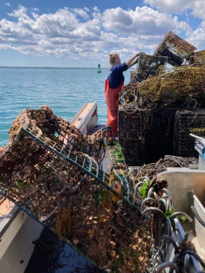 Crew member Cara Delaney stacks recovered lobster traps on April 19, 2021 off Plymouth aboard the F/V KESTREL. (Courtesy Caroline E. Howlett)