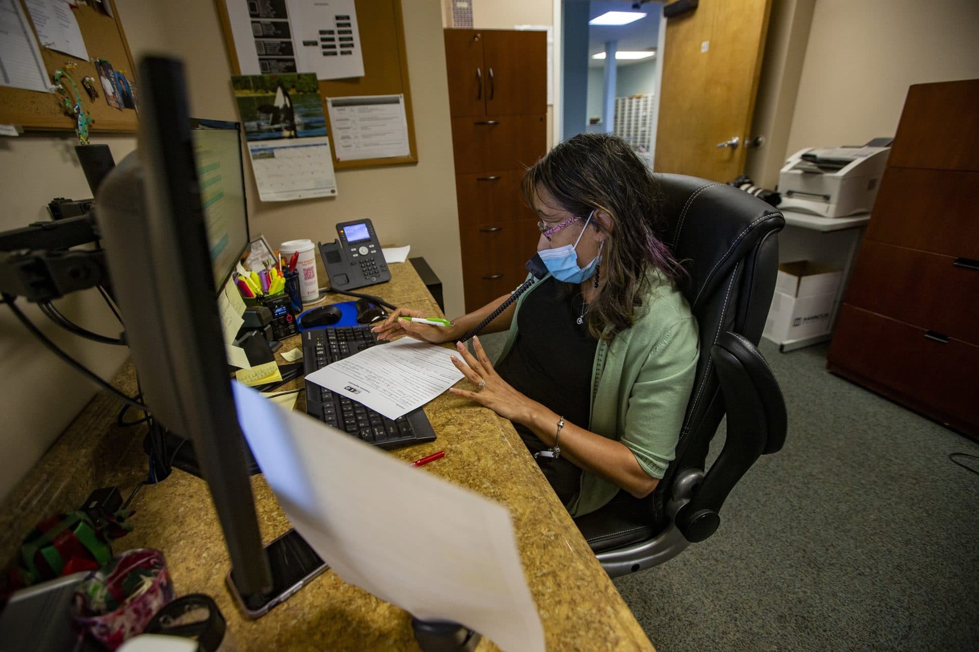 Administrative assistant Myrna Siler takes a call to request an appointment at the Outpatient Behavioral Health and Family Support Services office in Springfield. (Jesse Costa/WBUR)