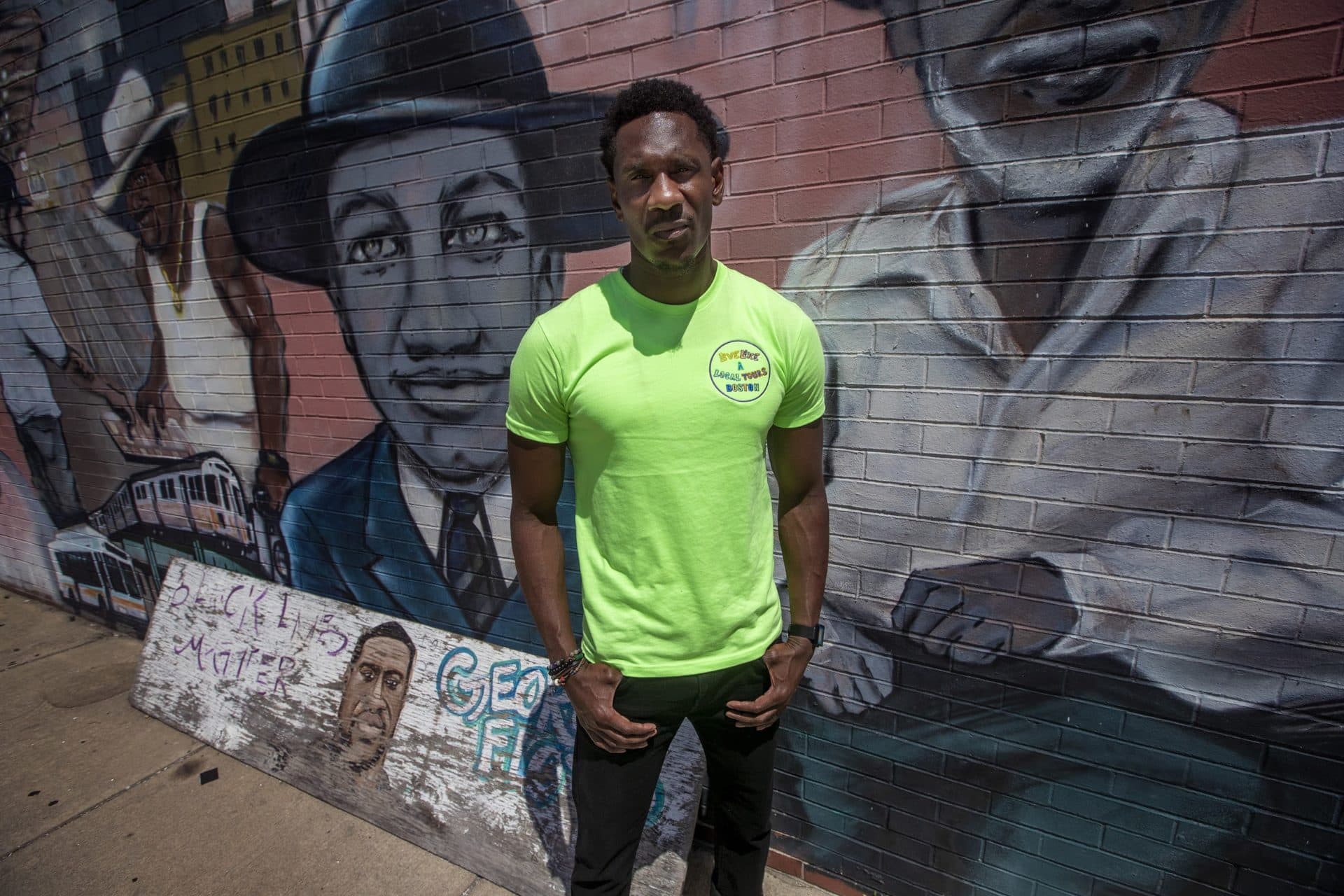 Collin Knight of Live Like a Local Tours at the ‘Faces of Dudley’ mural. (Jesse Costa/WBUR)