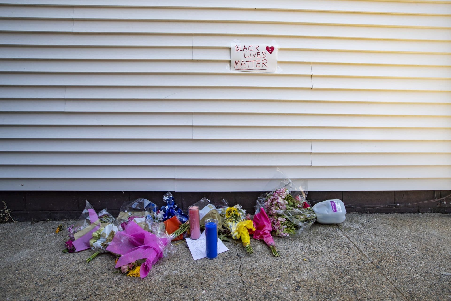 Flowers and candles lay in an alley way off of Shirly Street in Winthrop where retired Massachusetts State Police officer David Green was fatally shot. (Jesse Costa/WBUR)