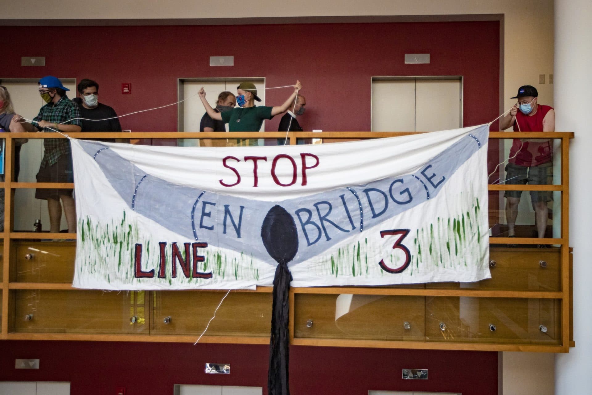 Protesters hang a banner protesting the Line 3 project, a crude oil pipeline replacement in Minnesota. (Jesse Costa/WBUR)