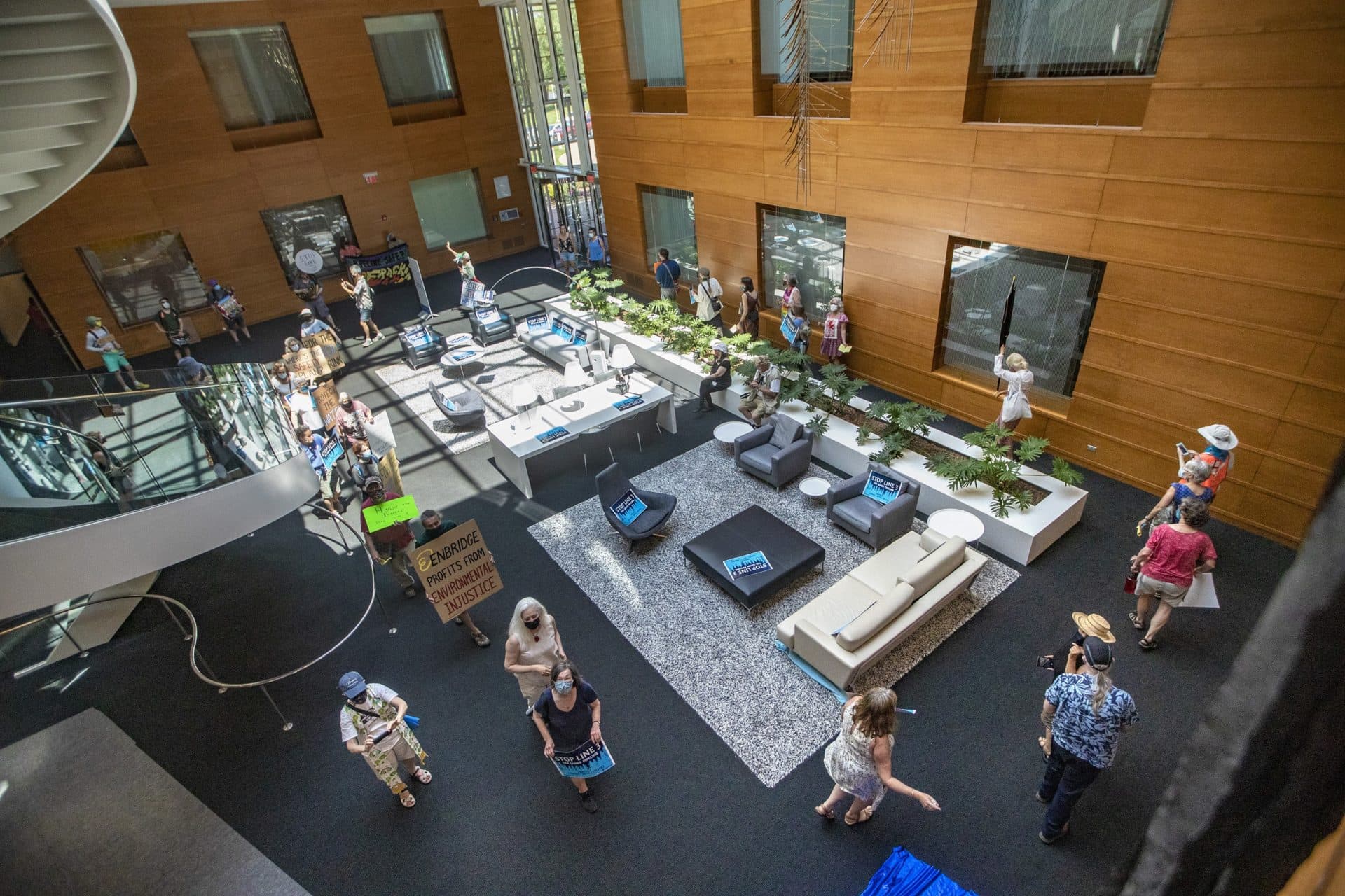 Protesters march around the lobby of the Enbridge office in Waltham. (Jesse Costa/WBUR)