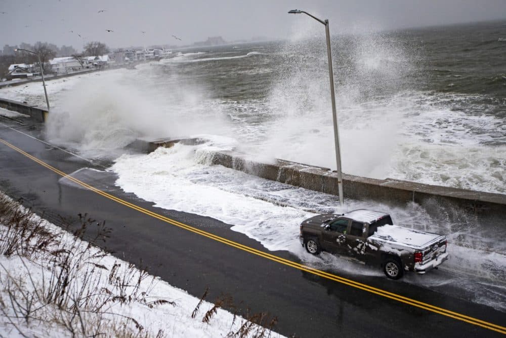 A pickup truck heads through flood water that has crashed over the seawall in Revere during a Nor’easter. (Jesse Costa/WBUR)