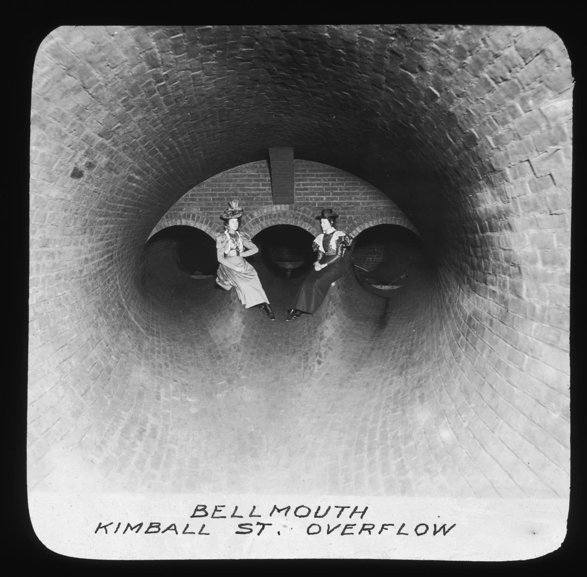 Two women sit inside a Boston sewer pipe in the 1880s. (Courtesy Boston Public Library)