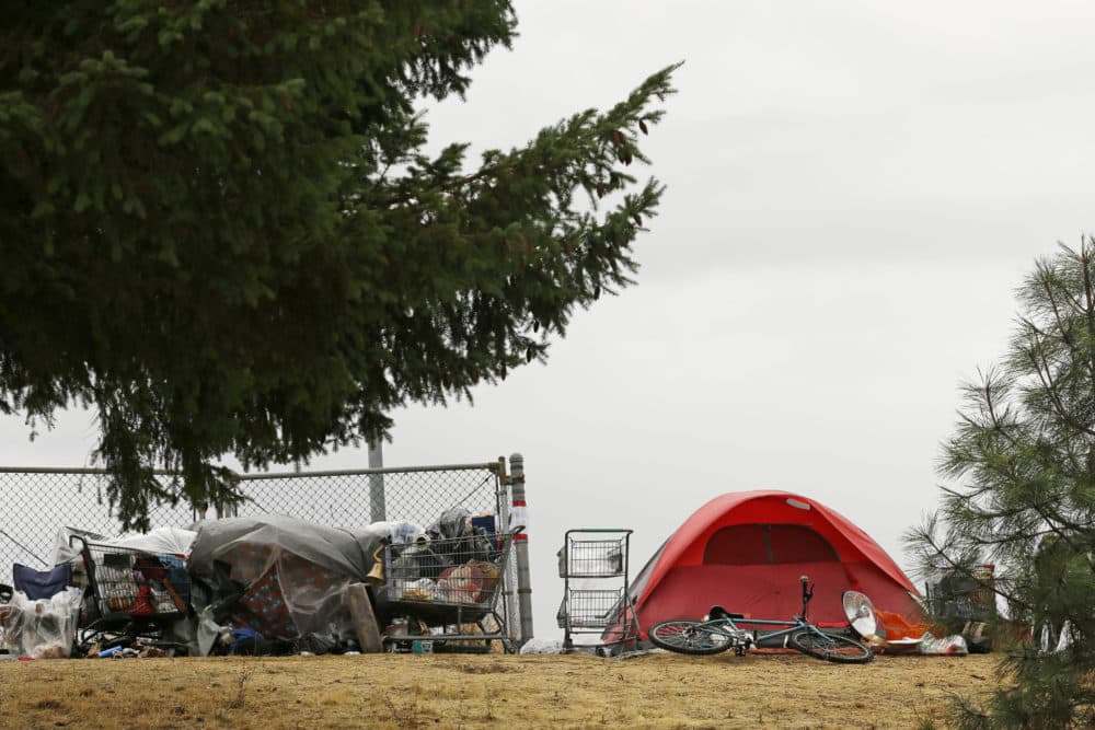A tent and shopping carts filled with belongings are near a neighborhood in Portland, Ore. (Ted S. Warren/AP/File)