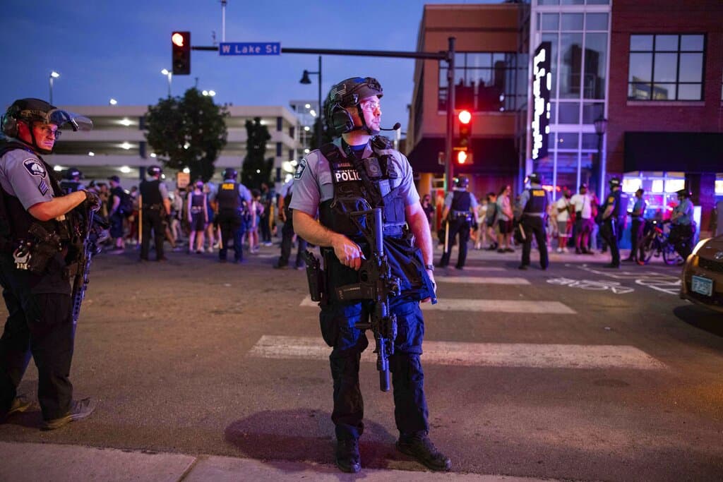 A police officer holds a firearm as community members gather on June 6 in Minneapolis, for Winston Boogie Smith Jr., who was fatally shot by members of a U.S. Marshals task force several days earlier. (Christian Monterrosa/AP Photo)