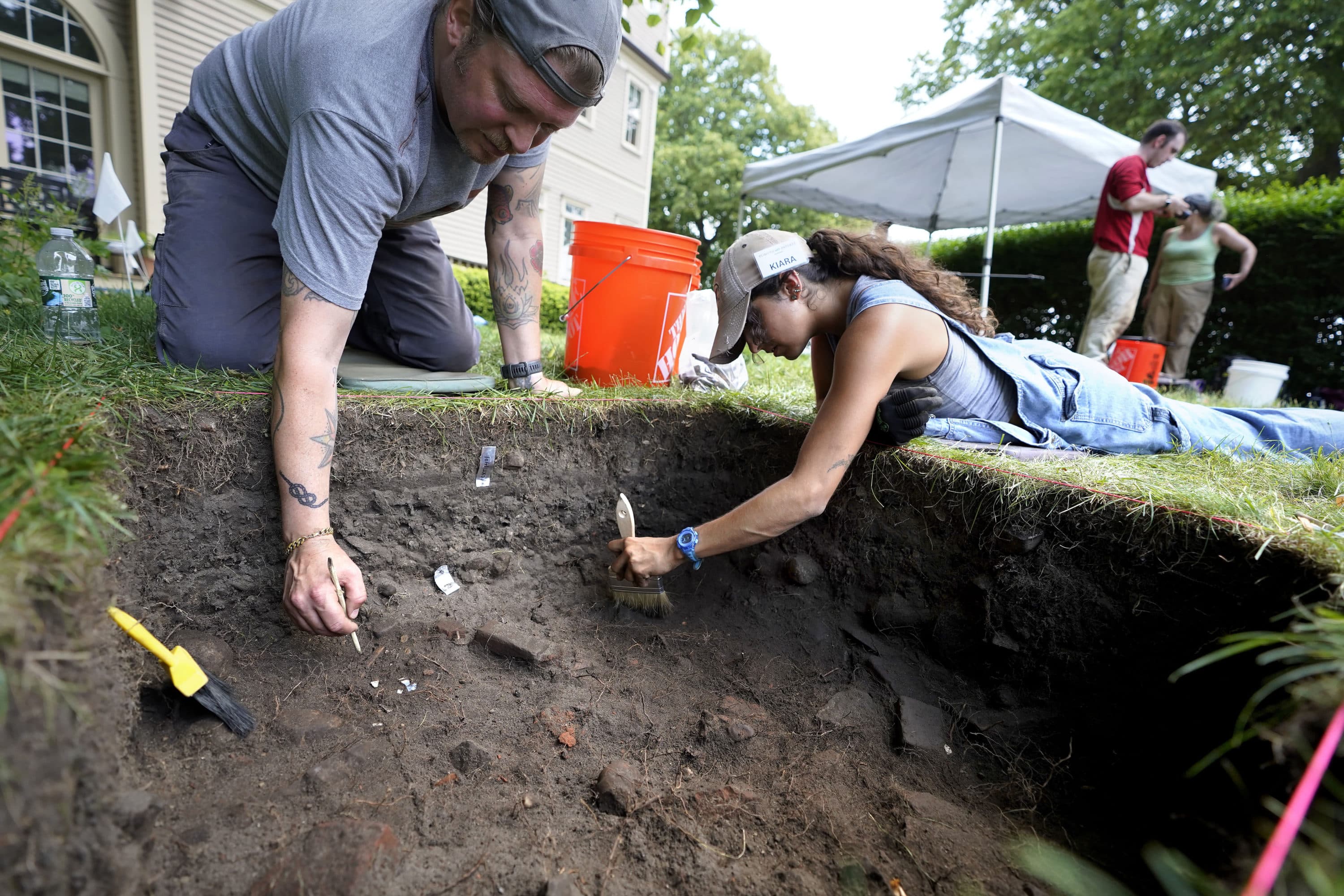 UMass Boston graduate students Nicholas Densley and Kiara Montes use brushes while searching for artifacts at the excavation site on Wednesday on Cole's Hill, in Plymouth. (Steven Senne/AP)