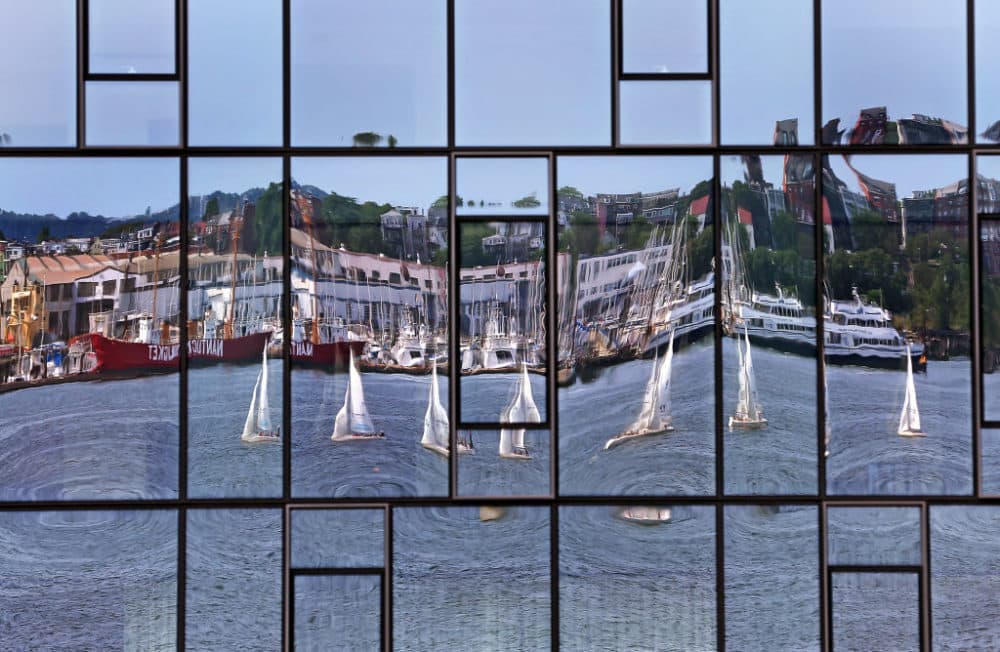 The glass of the Residences at Pier 4 Boston condominium complex in the Seaport neighborhood of Boston reflected sailboats on Boston Harbor on Aug. 14, 2019. (David L. Ryan/The Boston Globe via Getty Images)