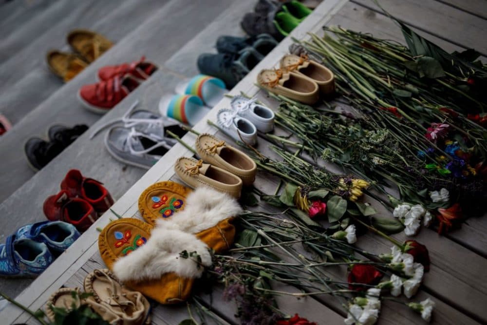 Flowers, shoes and moccasins sit on the steps of the main entrance of The Mohawk Institute, a former residential school for First Nation kids, to honor the 215 children whose remains were recently discovered in a mass grave at the former Kamloops Indian Residential School in British Columbia, Canada. (Cole Burnston/AFP/Getty Images)