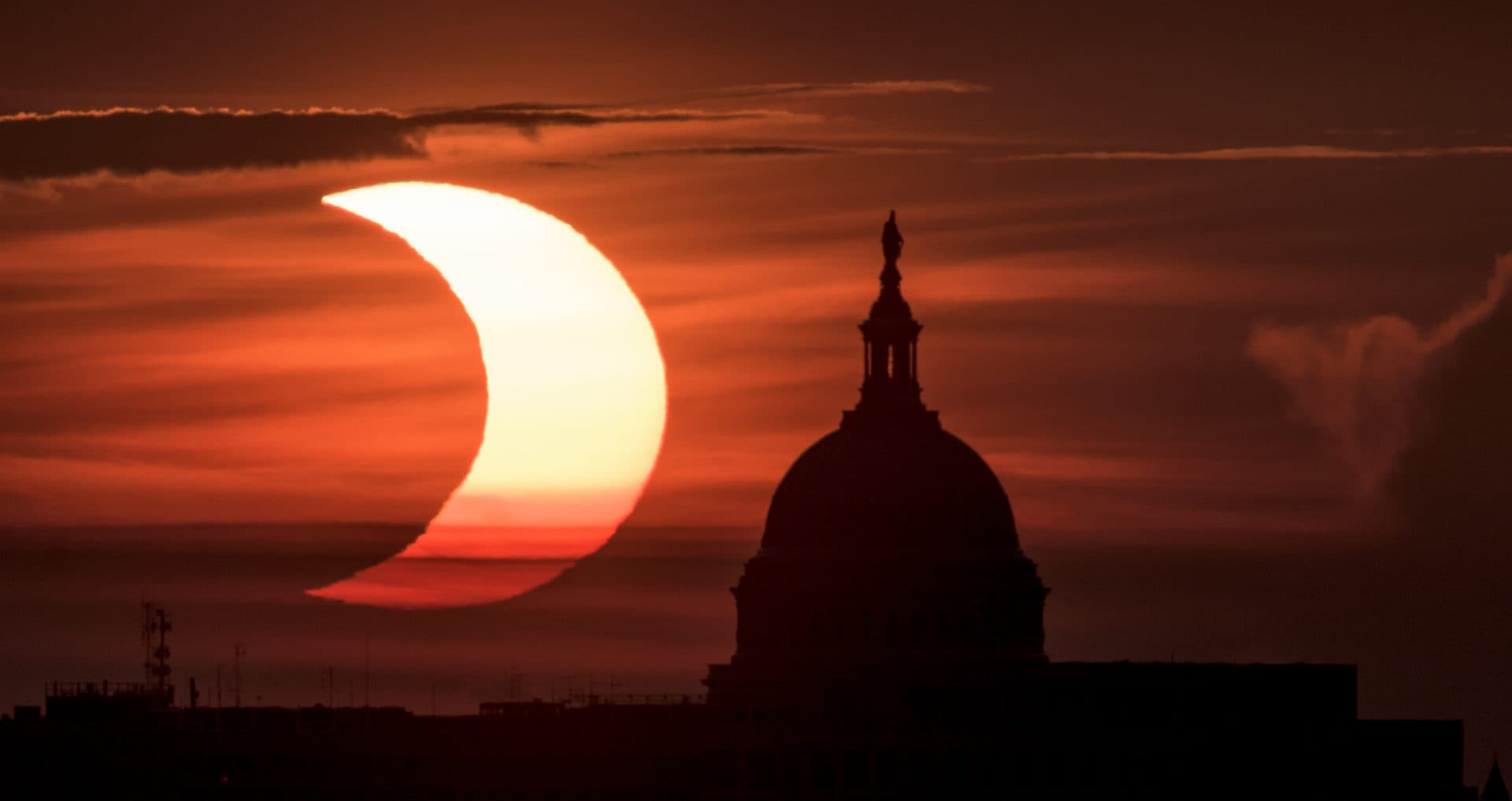 A partial solar eclipse is seen as the sun rises behind the Capitol Building on June 10, 2021 in Arlington, Virginia. (Bill Ingalls/NASA via Getty Images)