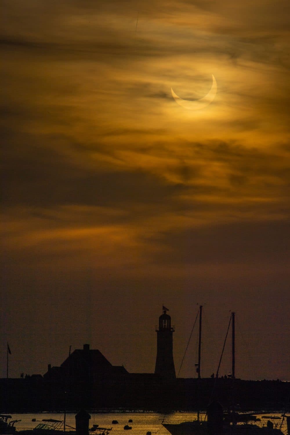 A annular (partial solar) eclipse is seen as the sun rises over Scituate Light in Scituate. (Joseph Prezioso/AFP via Getty)