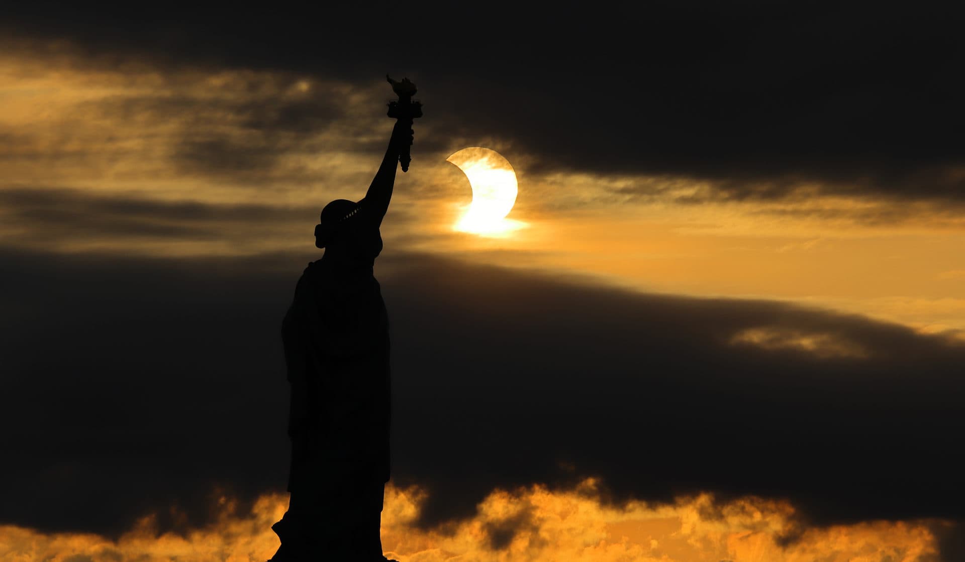 The sun rises next to the Statue of Liberty during an annular eclipse on Thursday in New York City. (Gary Hershorn/Getty Images)