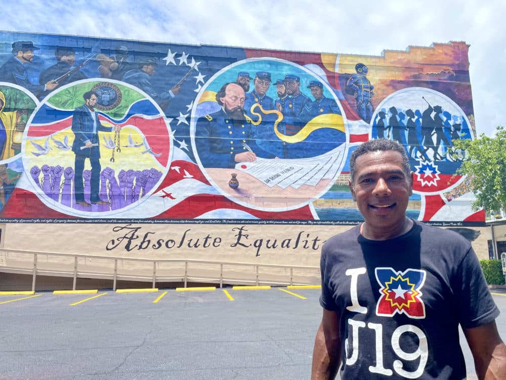 Houston-based public artist Reginald C. Adams stands in front of his Juneteenth mural “Absolute Equality” in Galveston, Texas. (Elizabeth Trovall/Houston Public Media)