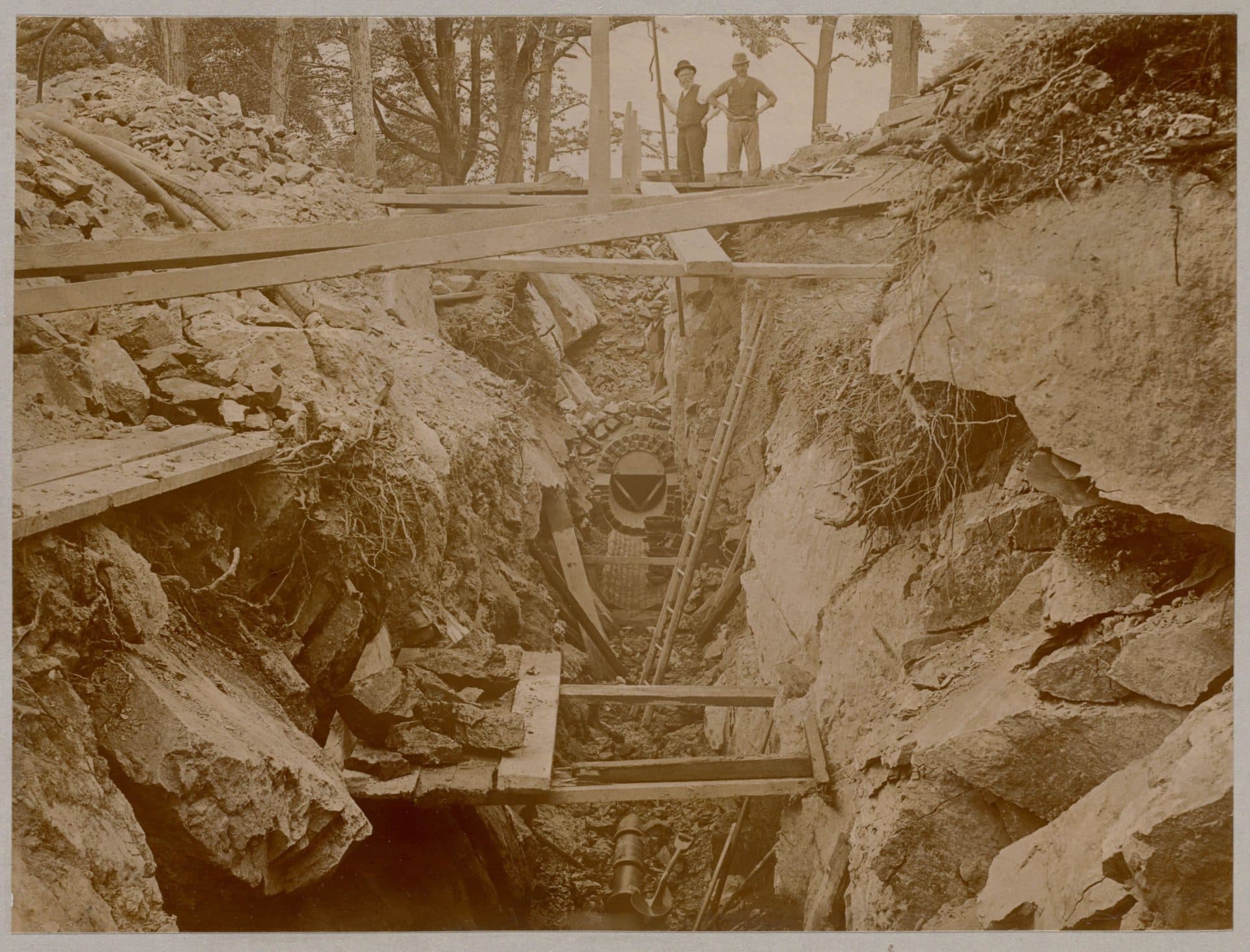 Men stand over unfinished sewer being built in the 1880s (Courtesy Boston Public Library)