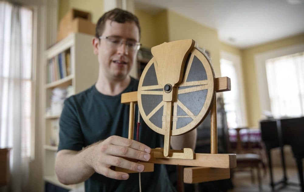 Bell ringer and statistician John Bihn uses a model to show how a bell can sit facing up just before it is rung. (Robin Lubbock/WBUR)