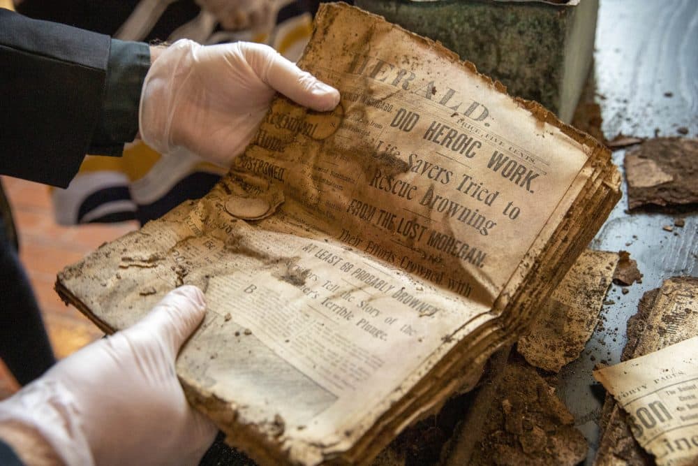 Rev. James Hopkins examines a newspaper found inside the 1898 copper box. (Robin Lubbock/WBUR)