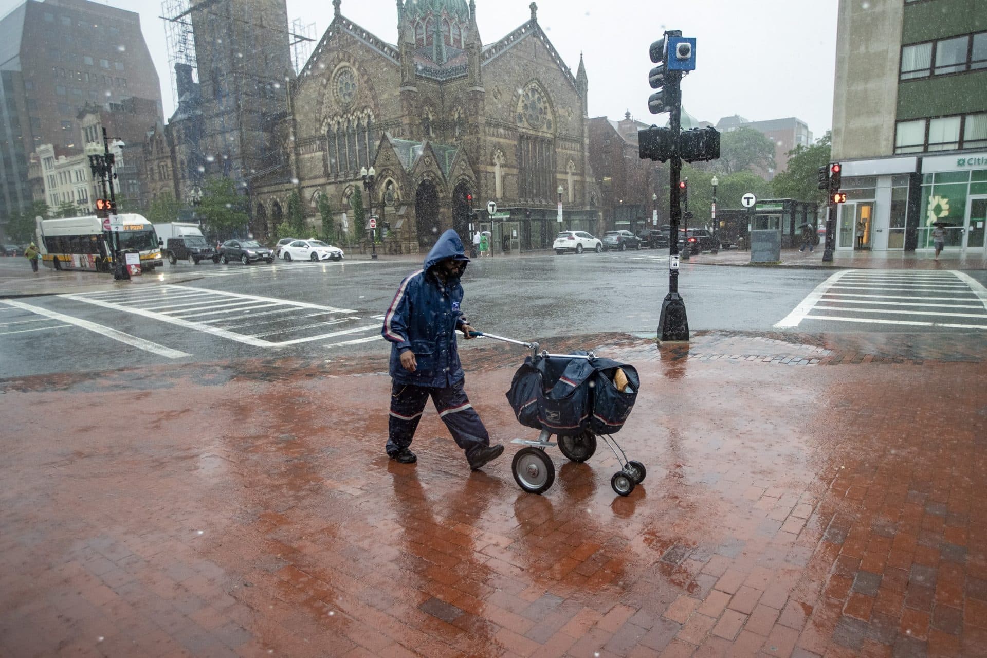 A mail carrier walks through the heavy rain in Copley Square during Tropical Storm Elsa. (Jesse Costa/WBUR)