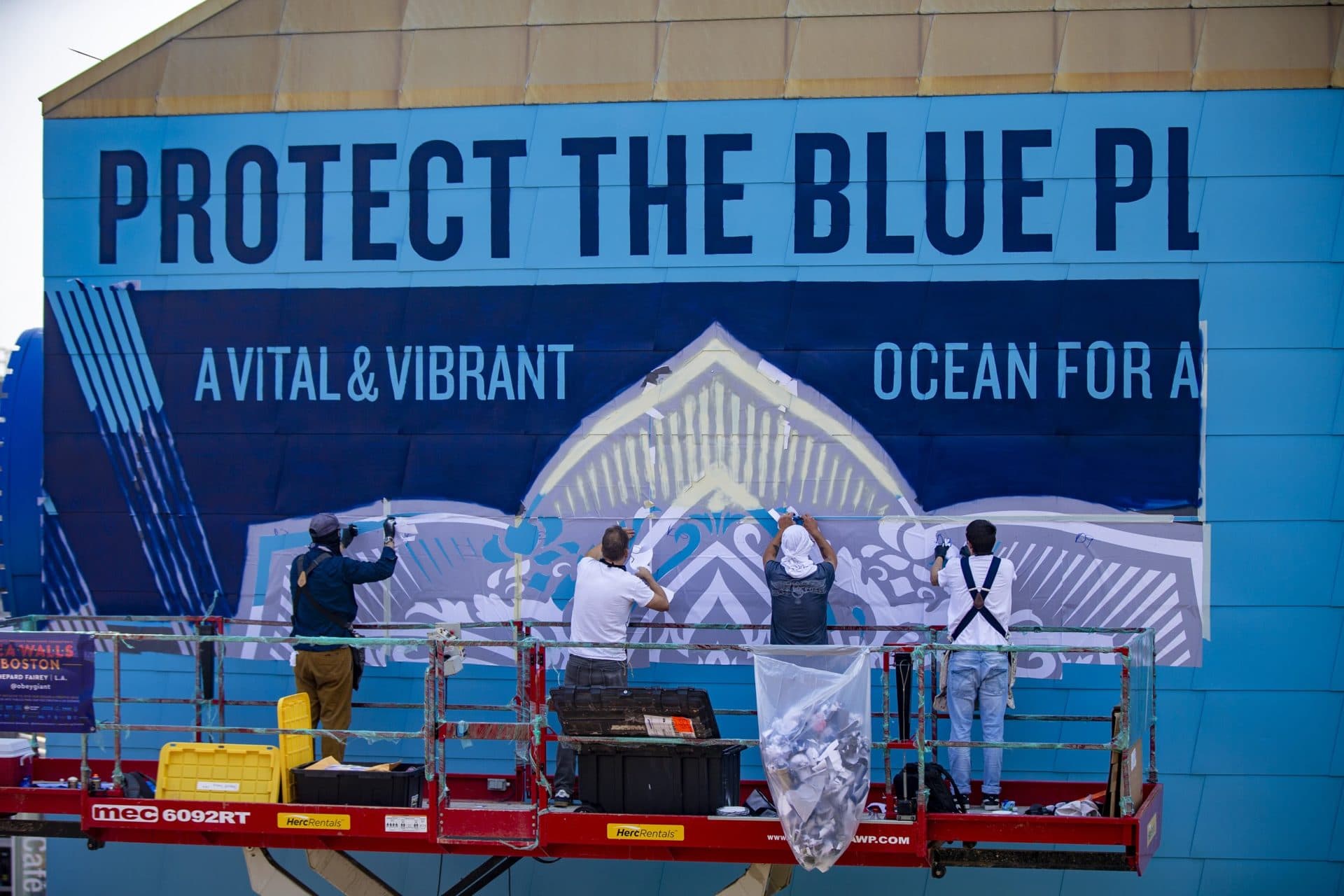 Shepard Fairy and his crew install the stencils for a mural on a wall of the IMAX Simons Theater at the New England Aquarium. (Jesse Costa/WBUR)