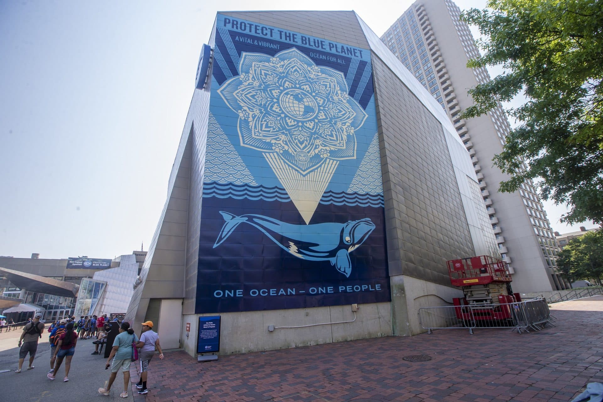 People walk past Shepard Fairey’s mural on their way to the aquarium. (Jesse Costa/WBUR)