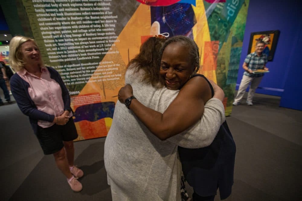 Ekua Holmes is embraced by Quincy Catholice Academy school teacher Carolyn Major, showing her appreciation for Holmes’ illustration work in children’s books. (Jesse Costa/WBUR)