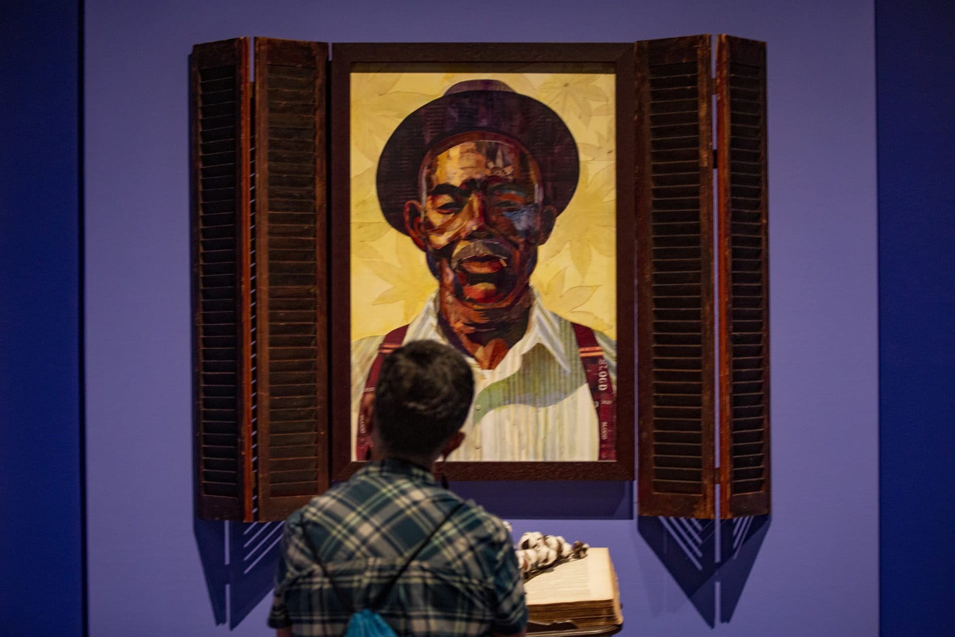 Emily Farmer examines “Idyll of the South: Root of Jesse” a work which features Ekua Holmes’ grandfather. (Jesse Costa/WBUR)